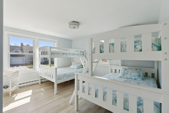 bedroom featuring a baseboard heating unit and wood finished floors