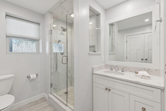 full bathroom featuring vanity, toilet, a marble finish shower, baseboards, and wood finished floors