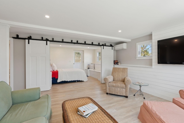 bedroom with recessed lighting, a wall unit AC, light wood finished floors, and a barn door
