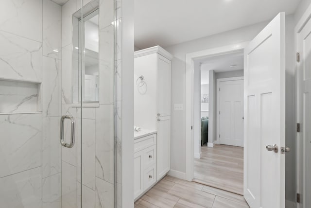 bathroom featuring a marble finish shower and vanity