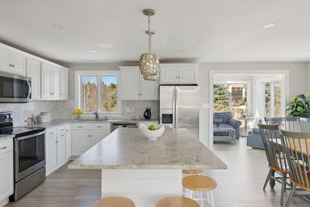 kitchen featuring a kitchen island, light wood-type flooring, tasteful backsplash, a sink, and stainless steel appliances