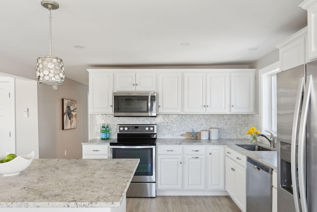 kitchen featuring white cabinetry, a sink, light wood-style flooring, backsplash, and stainless steel appliances
