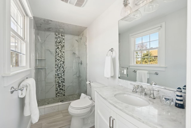 bathroom featuring toilet, visible vents, a marble finish shower, and vanity