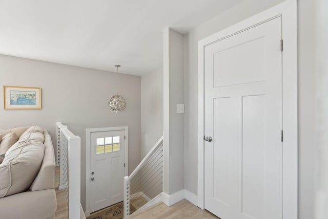 entryway with baseboards, a notable chandelier, and light wood-type flooring