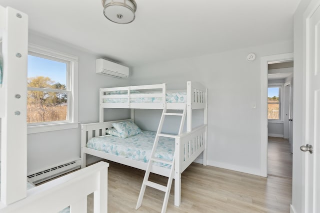 bedroom with multiple windows, a wall unit AC, a baseboard heating unit, and wood finished floors