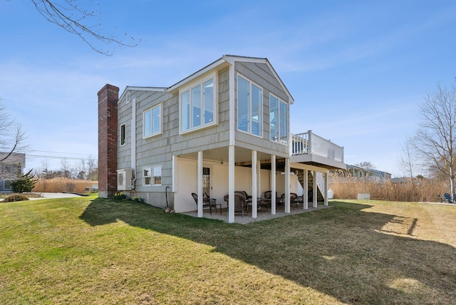 back of house featuring a chimney, a wooden deck, a yard, a patio, and stairs