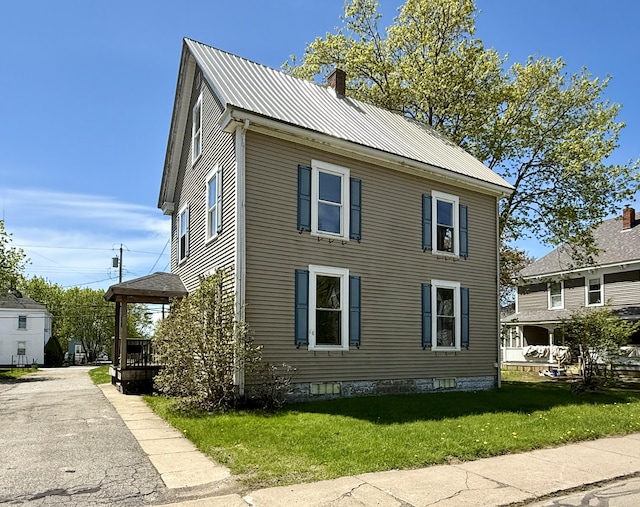 68 Washington St, Eastport, ME 04631 - view of property exterior with a chimney, a lawn, and metal roof
