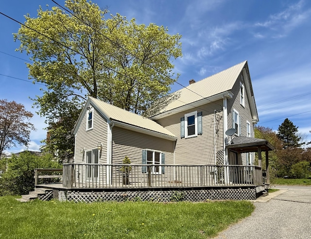 68 Washington St, Eastport, ME 04631 - view of home's exterior with a deck, metal roof, a chimney, and a lawn