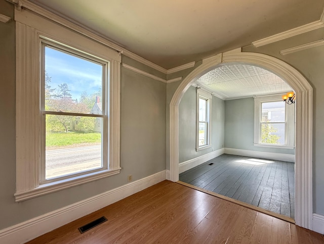 68 Washington St, Eastport, ME 04631 - spare room with hardwood / wood-style flooring, ornamental molding, arched walkways, and baseboards