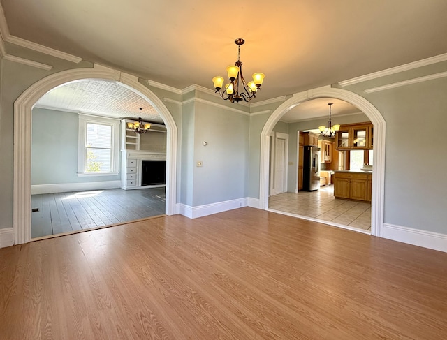 68 Washington St, Eastport, ME 04631 - unfurnished living room with a chandelier, arched walkways, light wood-style floors, baseboards, and ornamental molding