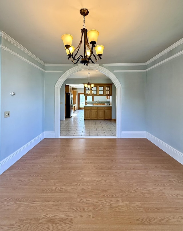 68 Washington St, Eastport, ME 04631 - unfurnished dining area with a chandelier, arched walkways, light wood finished floors, ornamental molding, and baseboards