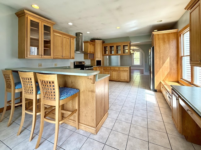 68 Washington St, Eastport, ME 04631 - kitchen featuring wall chimney exhaust hood, appliances with stainless steel finishes, a peninsula, a breakfast bar area, and recessed lighting