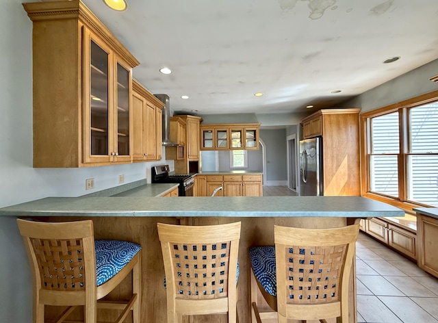 68 Washington St, Eastport, ME 04631 - kitchen featuring stainless steel appliances, wall chimney range hood, a kitchen bar, recessed lighting, and a peninsula