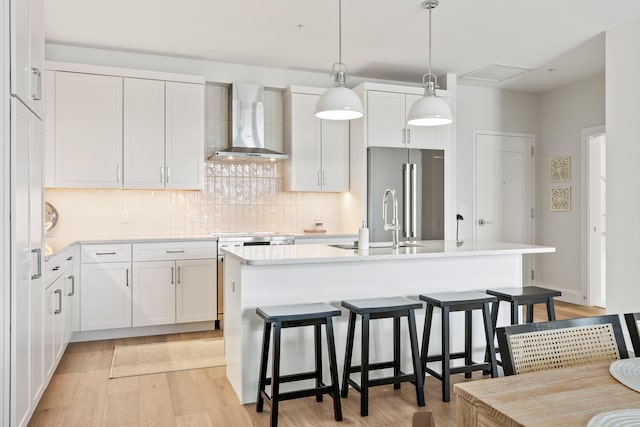 267 US Route 1 Ph 508, Falmouth, ME 04105 - kitchen with light wood-style floors, wall chimney exhaust hood, a kitchen breakfast bar, white cabinetry, and high end fridge