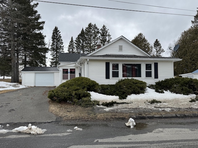 11 Pleasant St, Limestone, ME 04750 - view of front of property featuring an attached garage, an outbuilding, driveway, and a chimney