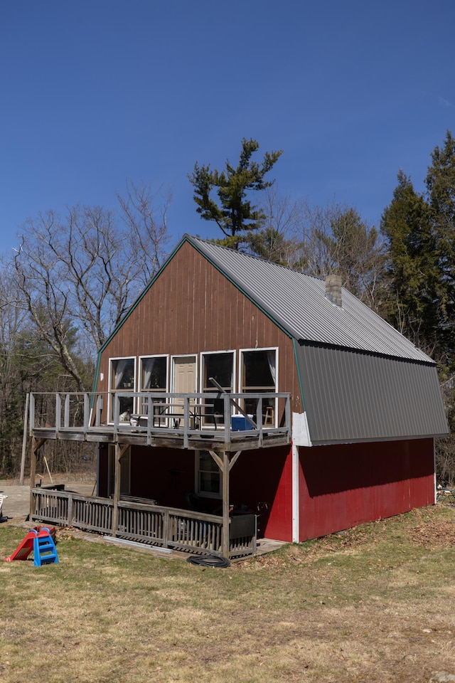 rear view of house featuring a lawn, a wooden deck, a gambrel roof, and metal roof
