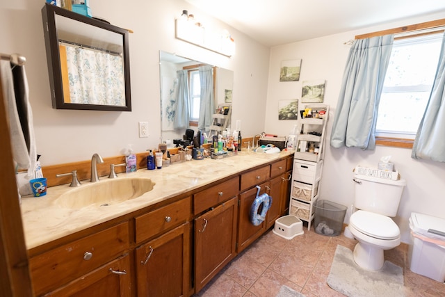 full bath with double vanity, tile patterned floors, toilet, and a sink