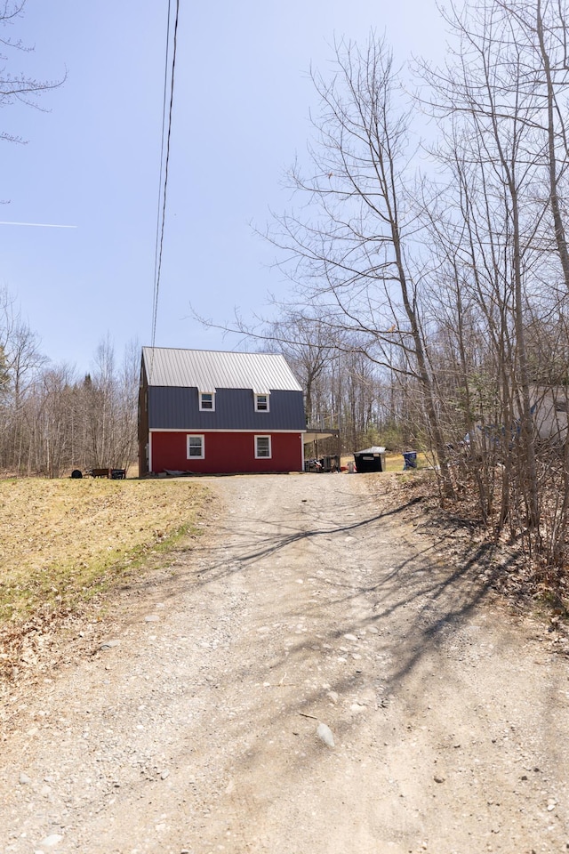 exterior space with dirt driveway and metal roof