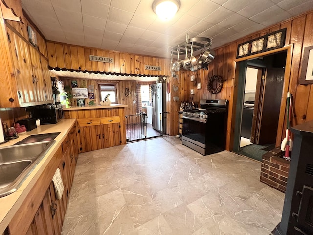 113 River Rd, Dresden, ME 04342 - kitchen with stainless steel appliances, wood walls, a peninsula, brown cabinetry, and light countertops