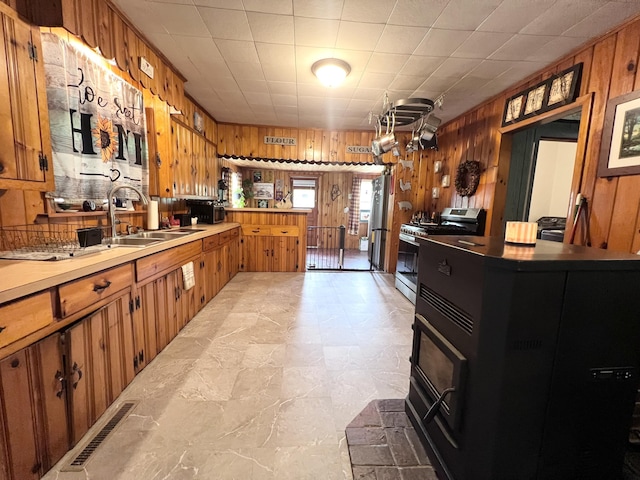 113 River Rd, Dresden, ME 04342 - kitchen with gas stove, wooden walls, brown cabinetry, a peninsula, and light countertops