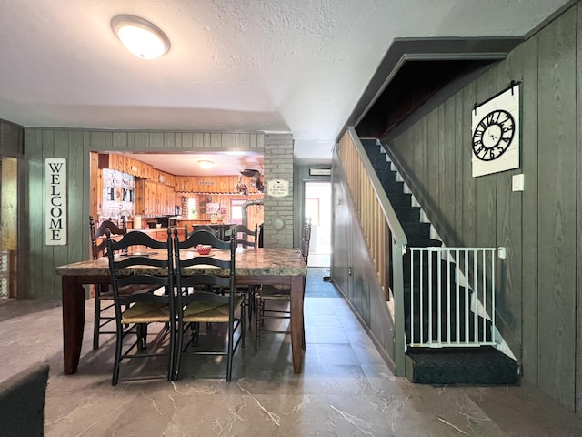 113 River Rd, Dresden, ME 04342 - dining area with wooden walls, a textured ceiling, and stairway