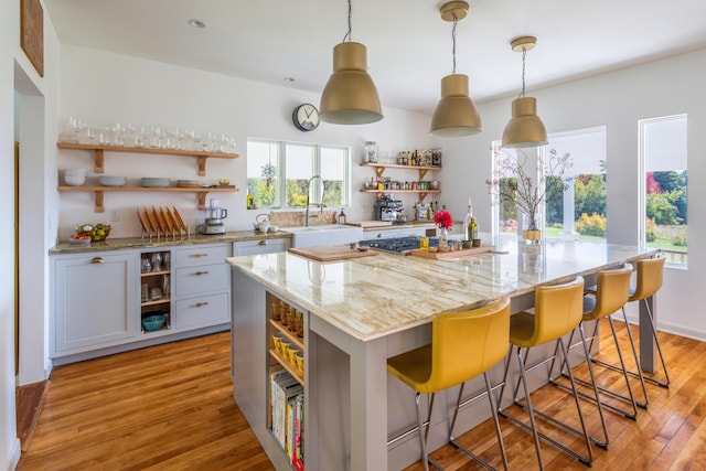 26 Old Searsport Ave, Belfast, ME 04915 - kitchen with open shelves, light stone countertops, a center island, a sink, and light wood finished floors