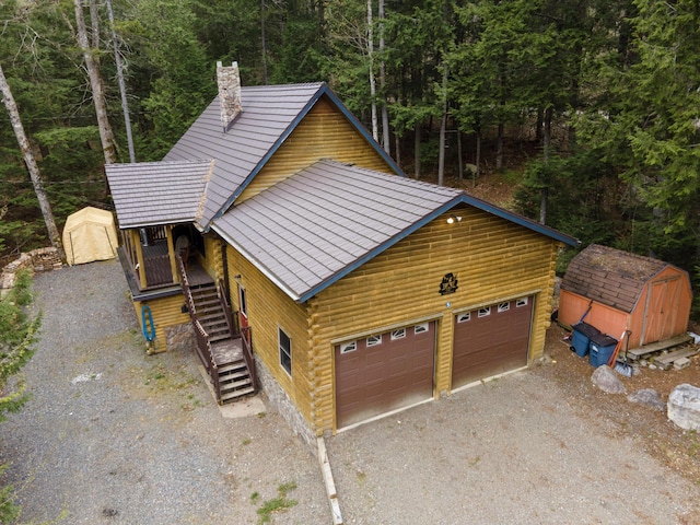 5 Canoe Ct Unit T3 R9, Nwp, ME 04462 - view of front of property with a storage unit, a chimney, an outbuilding, a wooded view, and driveway