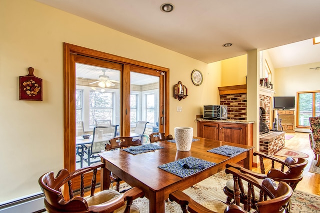 dining area featuring ceiling fan, light wood-type flooring, and a baseboard heating unit