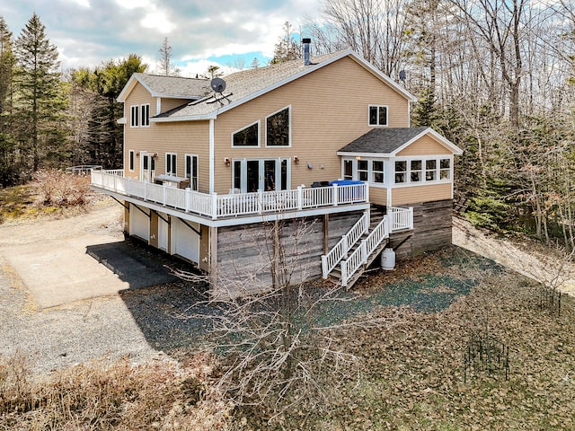 rear view of house with a sunroom, a shingled roof, stairway, a deck, and an attached garage