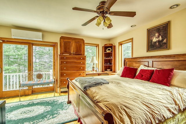 bedroom with a wall unit AC, light wood-style floors, access to exterior, recessed lighting, and a ceiling fan