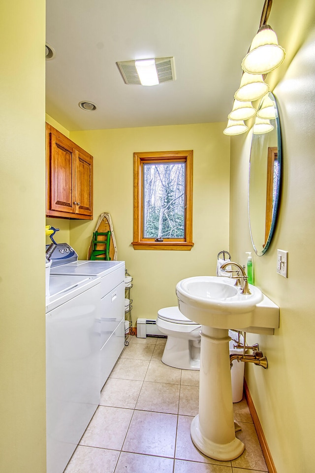 half bath featuring washing machine and clothes dryer, visible vents, a baseboard heating unit, toilet, and tile patterned flooring