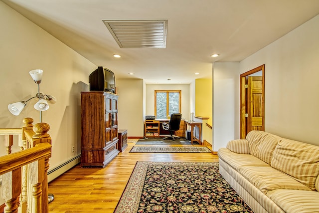 living area featuring baseboard heating, visible vents, light wood finished floors, and recessed lighting