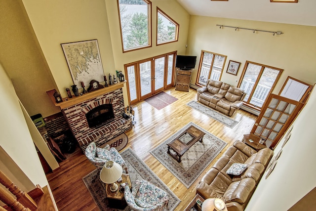 living room with wood finished floors, french doors, a fireplace, and a towering ceiling