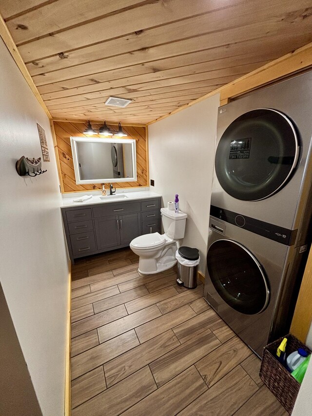 106 N Birch St, Greenville, ME 04441 - bathroom featuring stacked washer and clothes dryer, wood ceiling, toilet, wood finish floors, and vanity