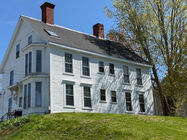 back of house with a chimney and a yard