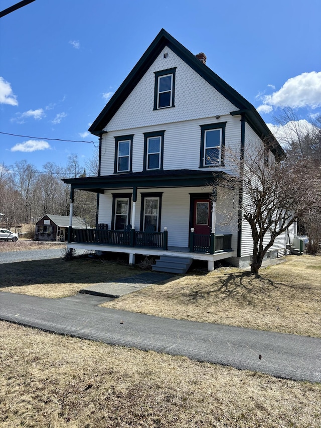 view of front of home featuring a chimney and covered porch