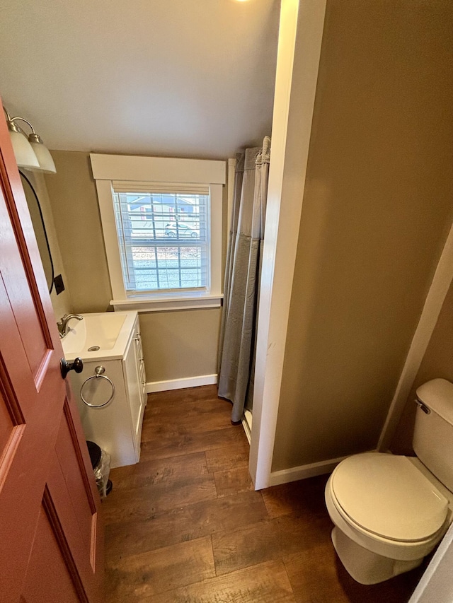 bathroom with toilet, wood finished floors, vanity, baseboards, and a shower with shower curtain