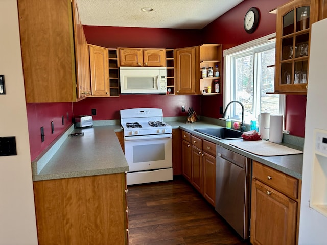 kitchen with a sink, dark wood-style flooring, glass insert cabinets, white appliances, and open shelves