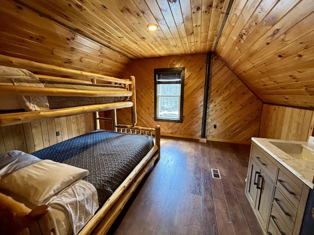 bedroom with wooden walls, wooden ceiling, vaulted ceiling, and dark wood finished floors