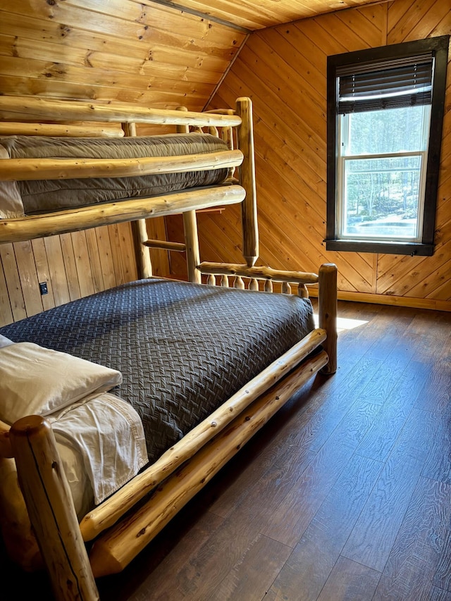 bedroom featuring vaulted ceiling, wooden walls, and hardwood / wood-style flooring
