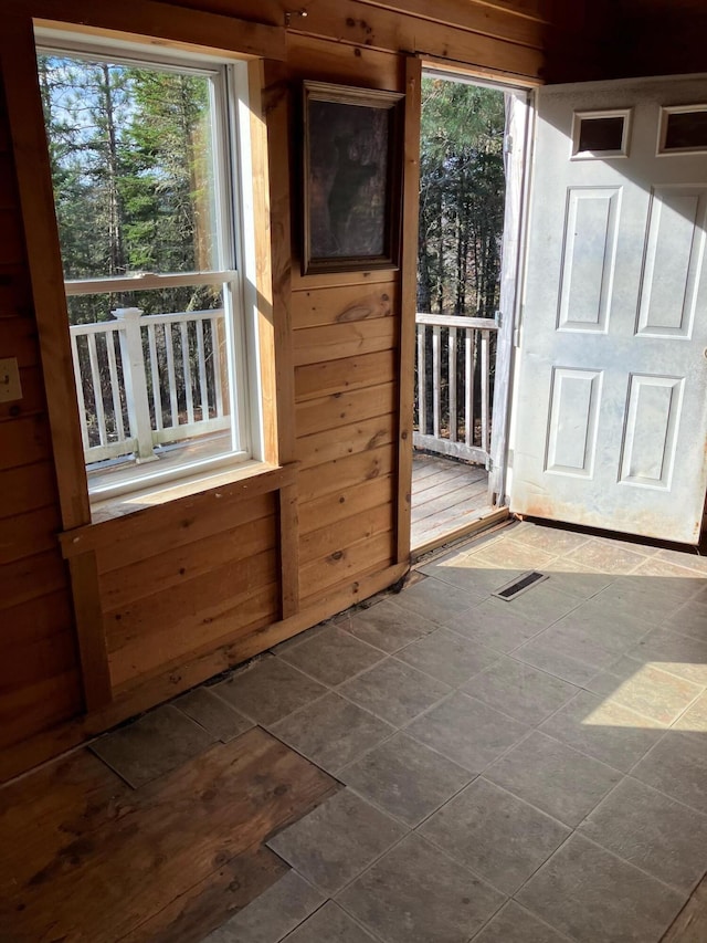 doorway to outside with a healthy amount of sunlight and wood walls
