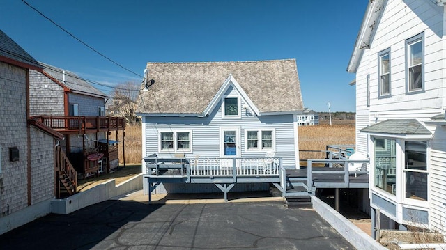 back of property with a wooden deck and a shingled roof