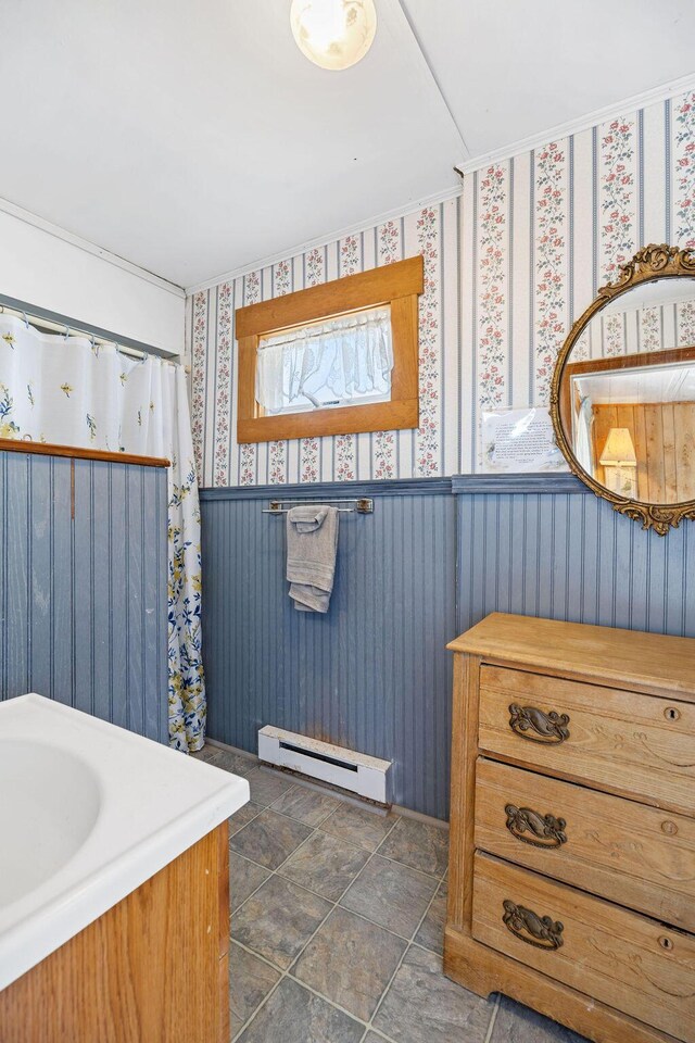 bathroom with wallpapered walls, a wainscoted wall, and a baseboard radiator