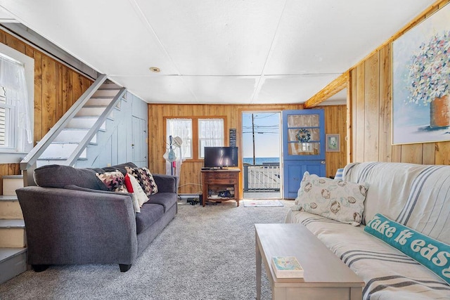 carpeted living room with wood walls and stairs