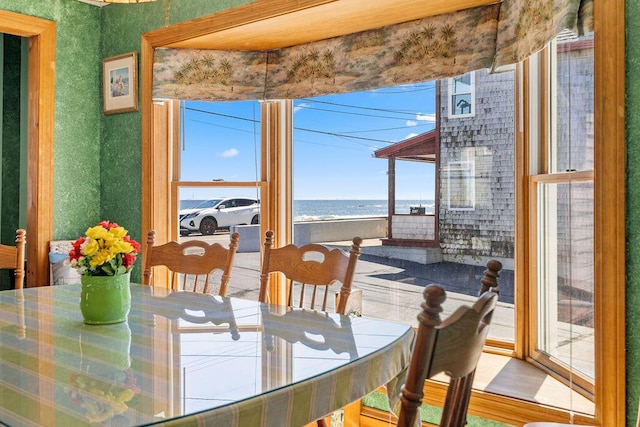 dining space with wallpapered walls and a water view