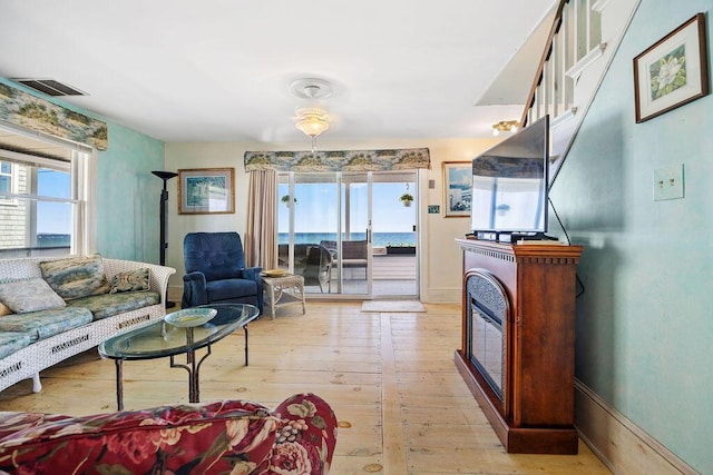 living area featuring light wood finished floors, visible vents, and a fireplace