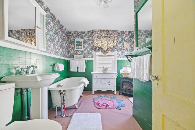 bathroom featuring wallpapered walls, a soaking tub, and tile walls