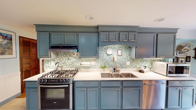 kitchen featuring light countertops, appliances with stainless steel finishes, a sink, and under cabinet range hood