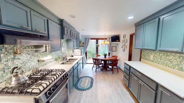 kitchen with under cabinet range hood, a sink, light countertops, and stainless steel gas range oven