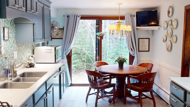 dining room featuring a wainscoted wall, light wood-type flooring, an inviting chandelier, and a baseboard heating unit